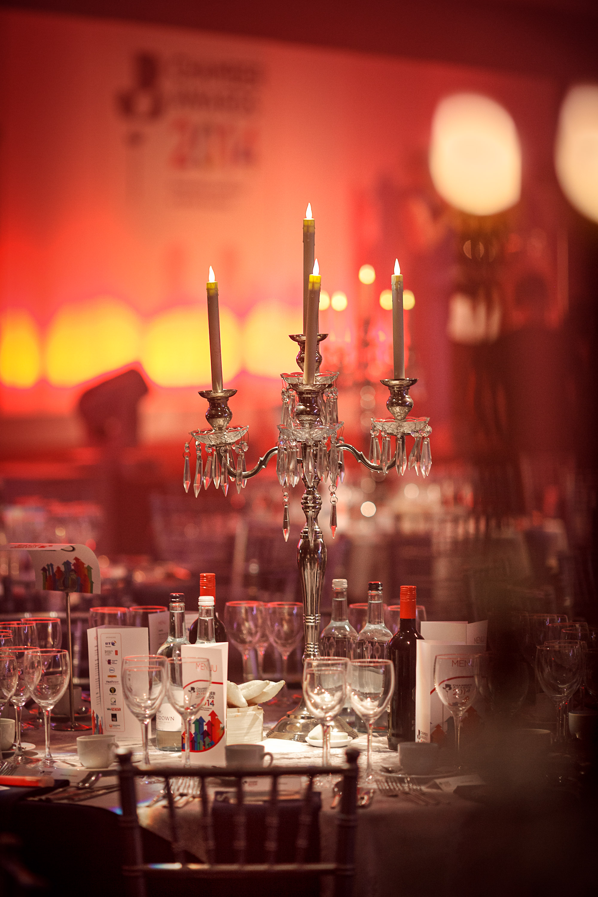 Awards event dinner table setting with candles and red lit backdrop