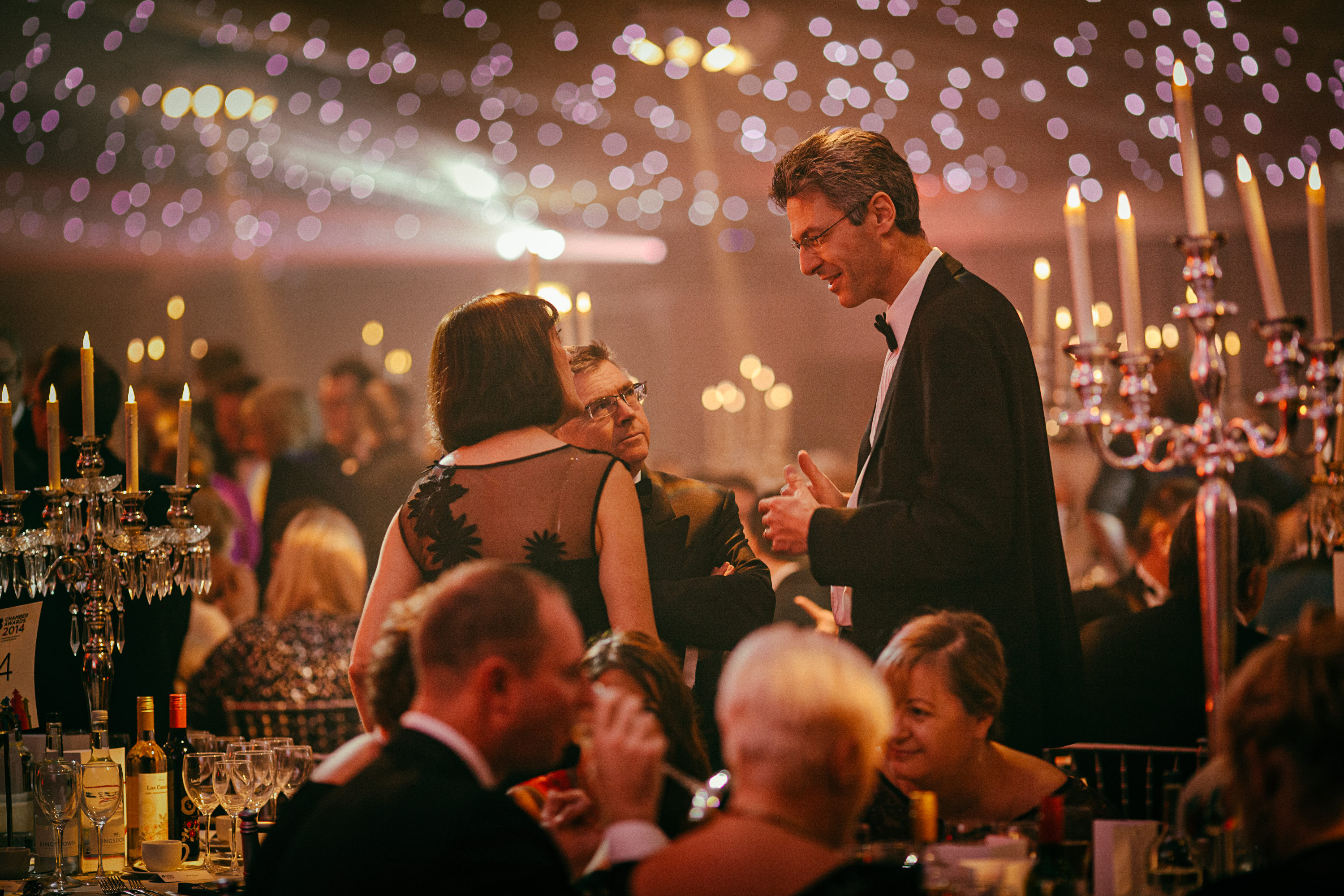 Glamorous corporate event with attendees chatting, bokeh lighting in the background