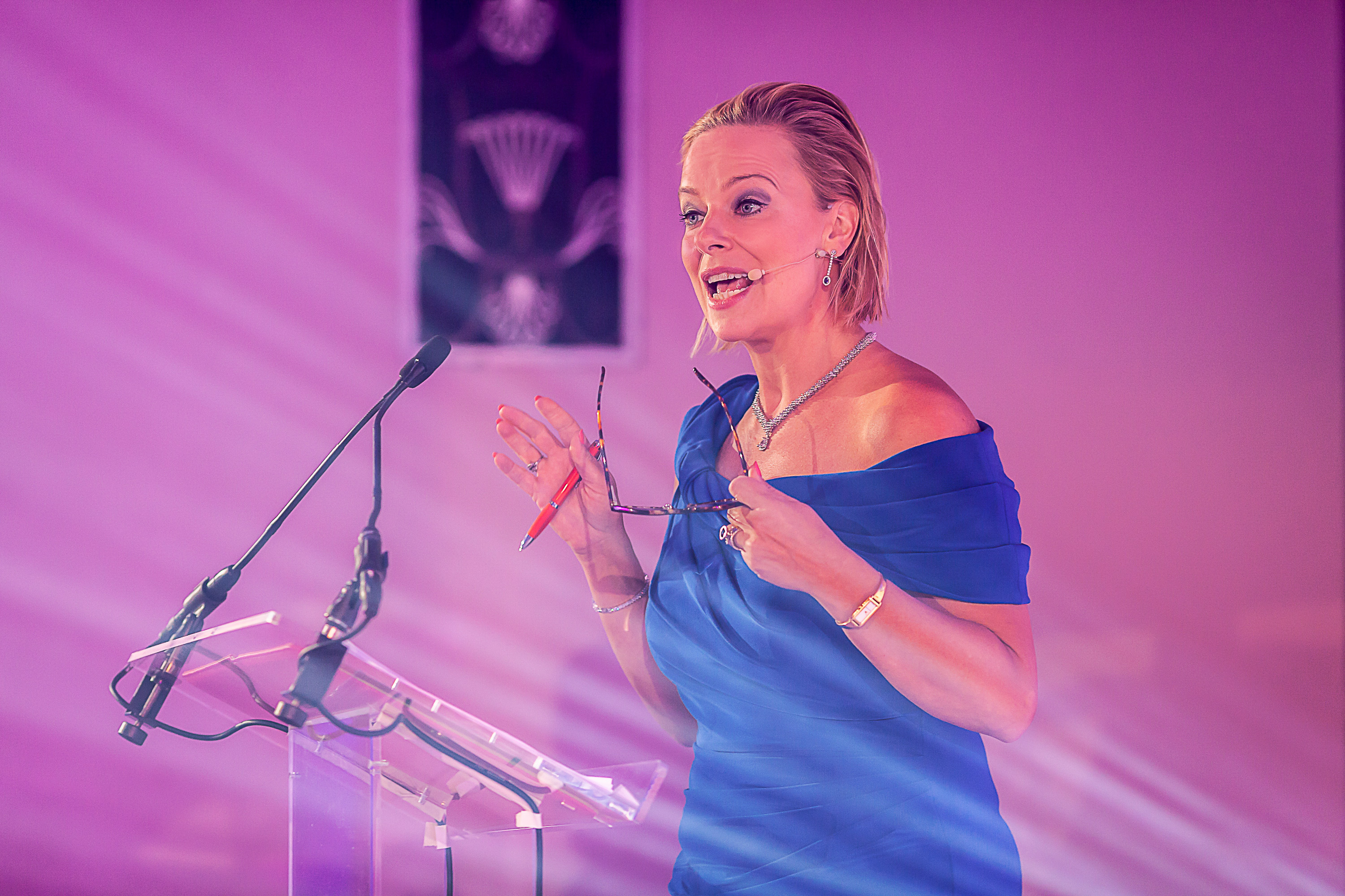 Event speaker wearing blue dress standing at a podium