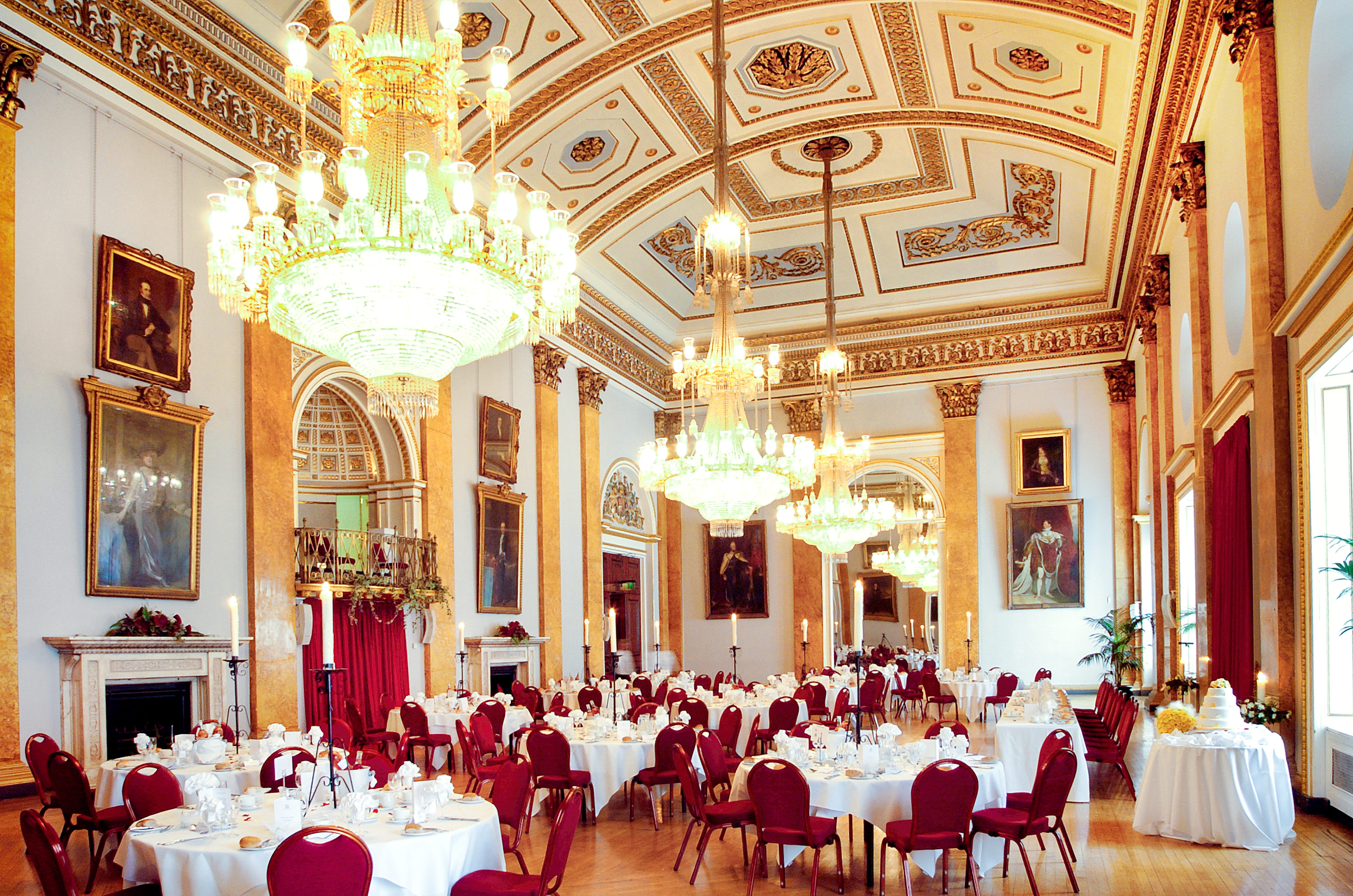 Tables set at a country house wedding venue with chandeliers and gold-framed portraits