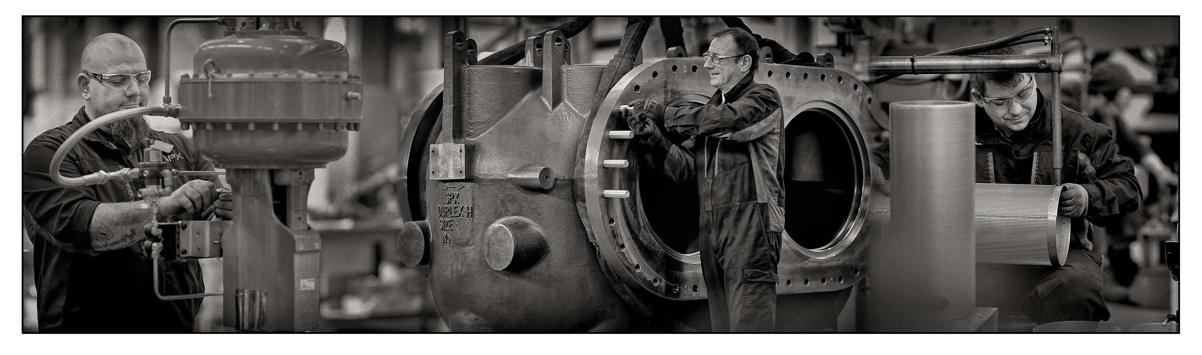 Grayscale photo of industrial production scene highlighting machinery and workers