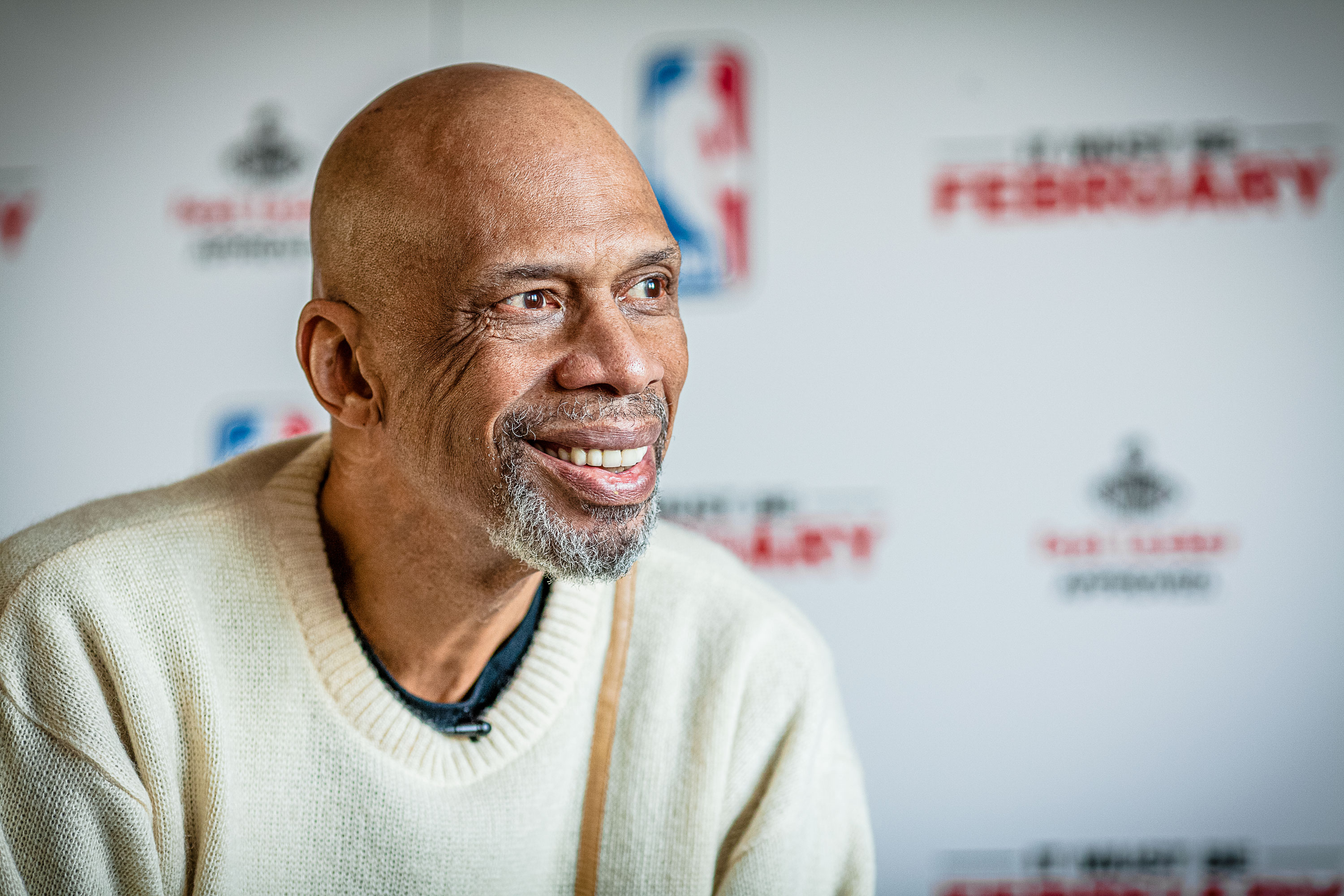 Sharp focus portrait of a man sitting in front of a logo backdrop