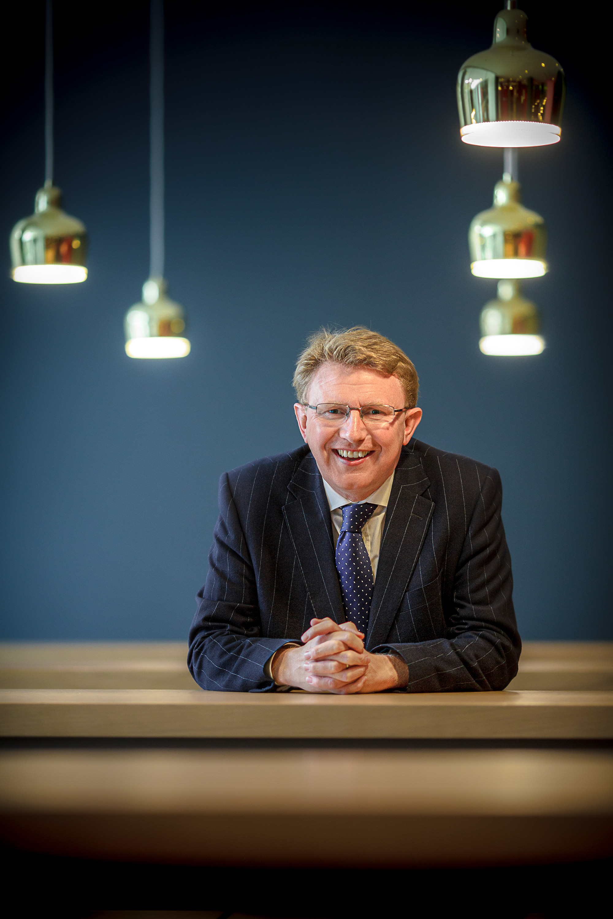 A smiling employee meet the team portrait with pendant lighting
