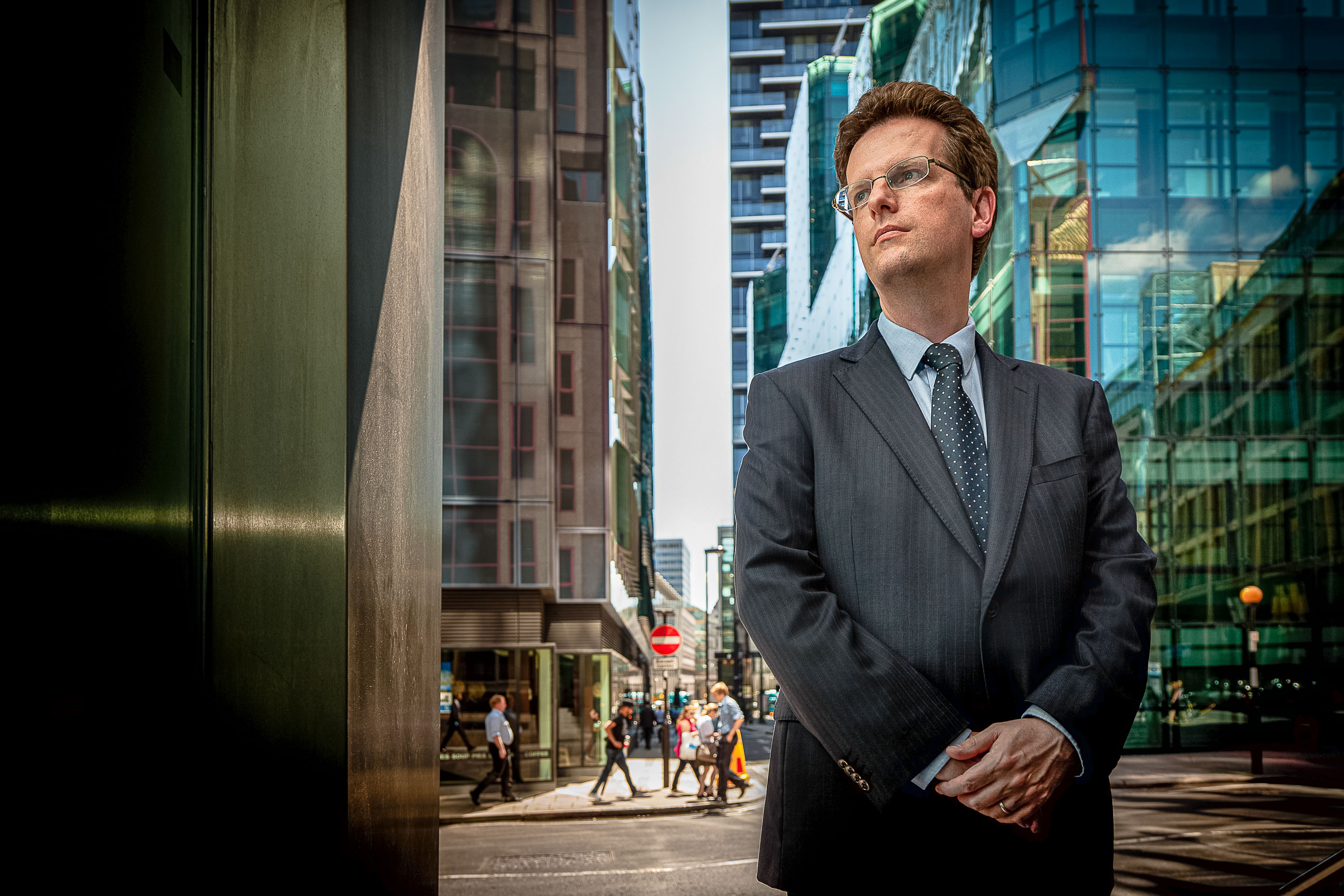 A business portrait of a man with office buildings and a busy street in the background, taken in London