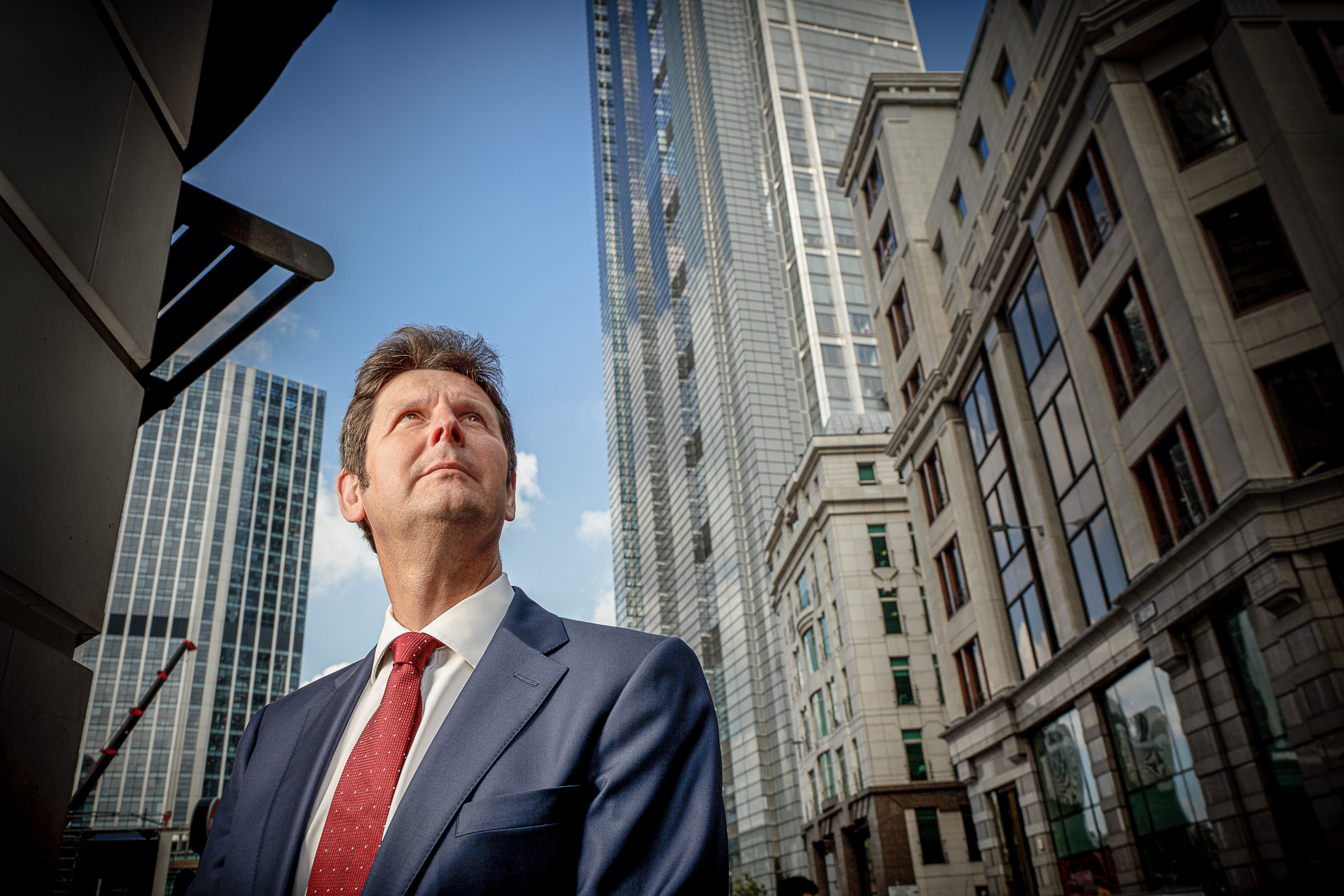 A business staff photo of a man with architectural office buildings