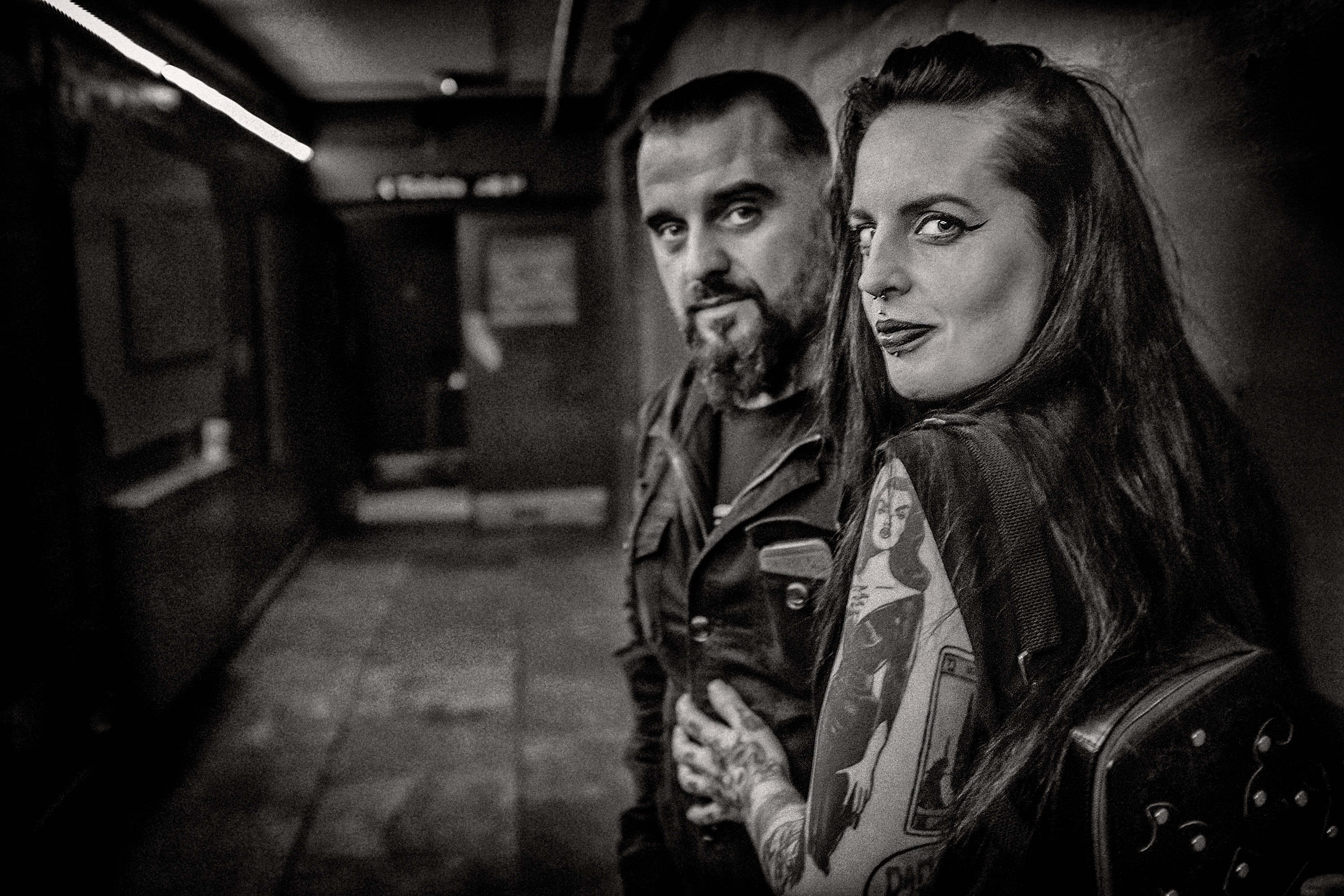 A black and white portrait of two people at a gig venue using